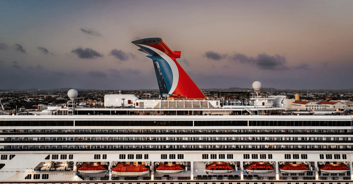 a large Carnival cruise ship docked in a harbor