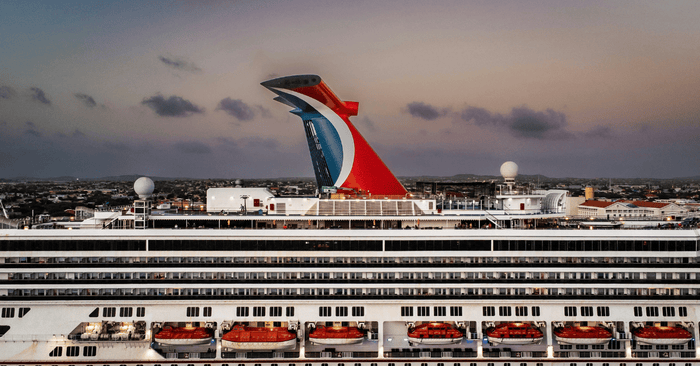 a large Carnival cruise ship docked in a harbor